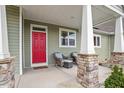 Inviting front porch with stone pillars, a bright red door, and comfortable seating area at 115 Mill Run Ln, Sanford, NC 27330