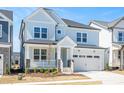 Inviting two-story home with light blue exterior, covered porch, stone accents, and attached two-car garage at 1245 Porters Call Dr, Wendell, NC 27591