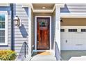 Inviting entryway features a wooden door, stylish lighting, and a glimpse of the attached garage at 1309 Pecora Ln, Raleigh, NC 27607