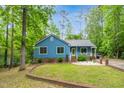 Charming blue home with a metal roof, well-manicured lawn, and inviting landscaping at 1487 Kentucky Ave, Sanford, NC 27332