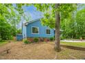 Exterior view of a blue single-story home with brick accents, and mature trees in a partially wooded setting at 1487 Kentucky Ave, Sanford, NC 27332