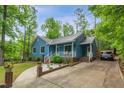 View of charming home featuring a metal roof, blue siding, front porch, a long driveway, and mature landscaping at 1487 Kentucky Ave, Sanford, NC 27332