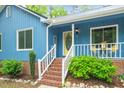 A close-up view of the charming front porch with brick steps, white railings, and a bright yellow front door at 1487 Kentucky Ave, Sanford, NC 27332