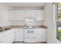 Well-lit kitchen featuring white cabinets, countertops, and appliances; window offers natural light at 359 Kilarney Dr, Durham, NC 27703