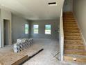 Open living area with stairs, large windows, and unfinished walls for a personalized touch at 54 Grove Township Way, Angier, NC 27501