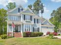 Charming two-story home with light-blue siding, black shutters, manicured landscaping, and an attached garage at 5708 Butter Churn Way, Fuquay Varina, NC 27526
