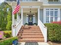 Inviting front porch with brick steps, white columns, and a classic black front door with decorative wreath at 5708 Butter Churn Way, Fuquay Varina, NC 27526