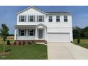 Charming two-story home with a well-manicured lawn, attached two-car garage, and classic architectural details at 59 Grove Township Way, Angier, NC 27501