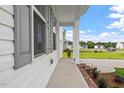 Inviting front porch with white columns, brick accents, and lush landscaping creating a welcoming entrance at 59 Grove Township Way, Angier, NC 27501