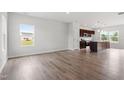 Open-concept living room featuring wood flooring, natural light, and seamless flow to the modern kitchen area at 59 Grove Township Way, Angier, NC 27501