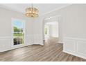 Elegant dining room with wood floors, decorative chandelier, wainscoting, and arched doorway at 6101 Clarks Fork Dr, Raleigh, NC 27616
