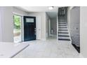 Open entryway with white tile flooring, black front door and staircase leading upstairs at 6409 Lakeland Dr, Raleigh, NC 27612