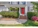 Close-up of the front entry featuring a red door, green shrubs, and manicured lawn at 709 Basil Dr, Durham, NC 27713