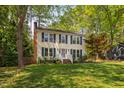 Inviting two-story home with a brick chimney, lush lawn, and mature trees creating a peaceful setting at 7433 Deer Track Dr, Raleigh, NC 27613