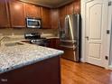 Well-lit kitchen featuring granite countertops, stainless steel appliances, and beautiful wood cabinetry at 8002 Upper Lake Dr, Raleigh, NC 27615