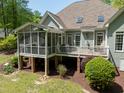 Rear exterior featuring a screened porch and deck overlooking a well-maintained lawn and wooded area at 8480 Falkirk Ridge Ct, Wake Forest, NC 27587