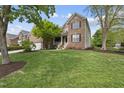 Charming brick home featuring a well-manicured lawn, lush landscaping, and inviting front porch at 9100 Dansforeshire Way, Wake Forest, NC 27587