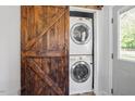 Laundry room with a stacked washer and dryer hidden behind a rustic barn door at 1017 Southerlund Rd, Garner, NC 27529