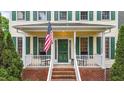Inviting front porch with rocking chairs, brick stairs, and an American flag at 1053 Loop Rd, Clayton, NC 27527