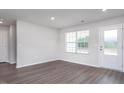 Bright living room featuring a large window, neutral walls, and stylish gray wood-look flooring at 11682 International Dr, Middlesex, NC 27557