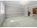Spacious, carpeted living room featuring elegant chandelier, crown molding, and neutral paint at 118 Shannon Dr, Burlington, NC 27215