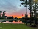 Tranquil view of houses reflecting on a pond under a colorful sunset at 240 Liberty Star Rd, Wendell, NC 27591