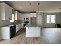Bright kitchen featuring white cabinets, a granite island with pendant lighting, and stainless steel appliances at 244 Bluejay St, Clayton, NC 27520