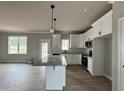 Bright kitchen featuring white cabinets, a granite island with pendant lighting, and stainless steel appliances at 244 Bluejay St, Clayton, NC 27520