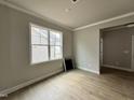 Cozy living room with hard wood floors, neutral paint, crown molding, and a large window at 244 Bluejay St, Clayton, NC 27520
