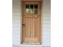 An elegant and stately natural wood front door framed by light gray wood siding at 2654 Lawndale, Durham, NC 27705