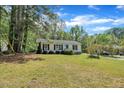 Quaint home features lush green lawn with lots of mature trees surrounding the house at 308 Plaza Dr, Garner, NC 27529