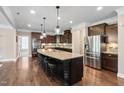 Modern kitchen with an island and seating, stainless steel appliances, dark cabinets, and hardwood flooring at 521 Wildwood Farm Way, Holly Springs, NC 27540