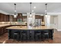 Kitchen featuring a large center island with seating, granite countertops, dark cabinetry, and stainless steel appliances at 521 Wildwood Farm Way, Holly Springs, NC 27540