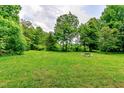 Expansive grassy yard, framed by mature trees, offers ample space and a rustic firepit at 6238 Old 421 Rd, Liberty, NC 27298