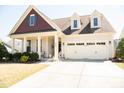 Charming home with a two-car garage, dormer windows, landscaped yard, and a welcoming front porch at 828 Traditions Ridge Dr, Wake Forest, NC 27587
