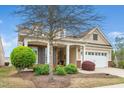 Inviting home showcasing manicured landscaping, a mature tree, and a covered porch with brick and column accents at 833 Gaston Manor Dr, Durham, NC 27703
