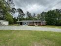 View of a charming brick house with a covered carport, complemented by a vast lawn at 8535 Us-301 S Hwy, Four Oaks, NC 27524