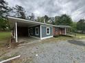 Angle view of a brick home showcasing a covered carport, and gravel driveway at 8535 Us-301 S Hwy, Four Oaks, NC 27524