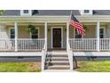 Inviting front porch with classic columns, hanging plants, and an American flag at 8700 Crowder Rd, Raleigh, NC 27603