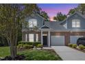 Charming two-story home with landscaped yard and mature trees at dusk at 9005 River Estates Dr, Knightdale, NC 27545