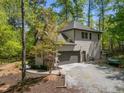 View of home featuring an attached two-car garage with gravel driveway surrounded by mature trees in a neighborhood setting at 107 Deer St, Carrboro, NC 27510
