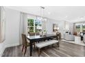 A bright dining room features wood floors, a modern chandelier, a large window, and an adjacent living area at 1132 Topaz Cave Cir, Raleigh, NC 27610