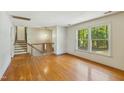 Bright living room featuring hardwood floors, large windows, and stairs leading to the upper level at 2211 Hillock Dr, Raleigh, NC 27612