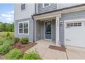 Close-up of home entrance featuring a stylish blue door and manicured landscaping at 2434 Heron Watch Pl, Fuquay Varina, NC 27526