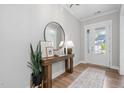 Bright entryway with wood floors, white trim, a console table, and a front door with sidelights at 261 Emory Bluffs Dr, Holly Springs, NC 27540
