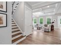 Staircase leading to a bright living room with coffered ceilings and large windows at 261 Emory Bluffs Dr, Holly Springs, NC 27540