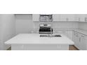 Kitchen island with stainless steel sink, modern faucet, white cabinets and stainless oven at 433 Providence Springs Ln, Fuquay Varina, NC 27526