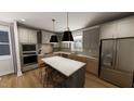 Modern kitchen featuring stainless steel appliances, gray cabinets, hardwood floors and a large kitchen island at 524 Folk Song Way, Wendell, NC 27591