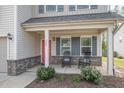 Charming front porch with rocking chairs, brick accents, a red front door, and meticulously maintained landscaping at 528 Holden Forest Dr, Youngsville, NC 27596