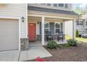 Inviting front porch featuring a bright red door, rocking chairs, and manicured landscaping details at 528 Holden Forest Dr, Youngsville, NC 27596